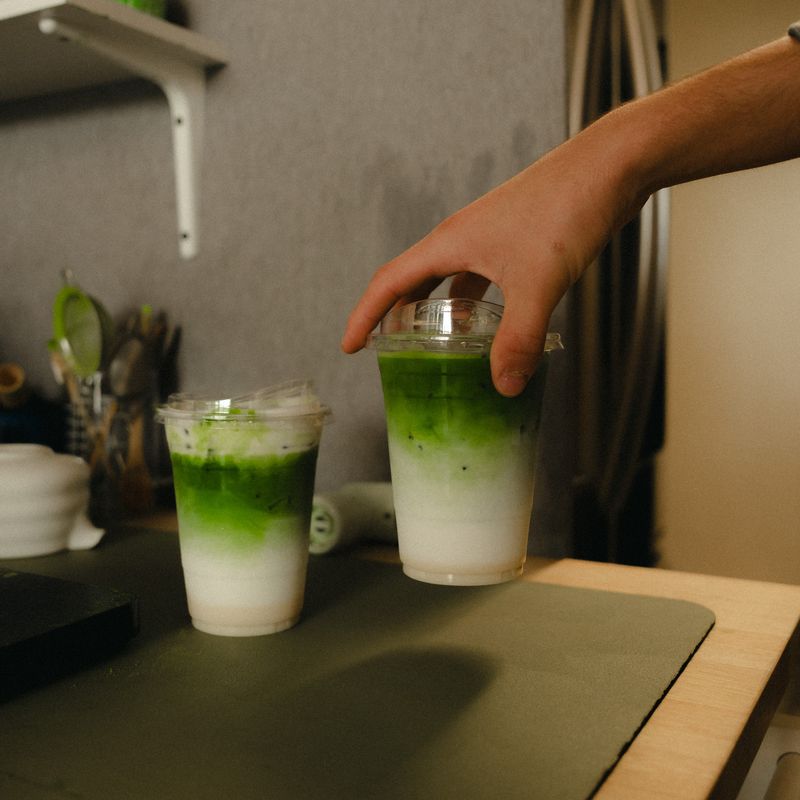 Two matcha drinks being made at the counter